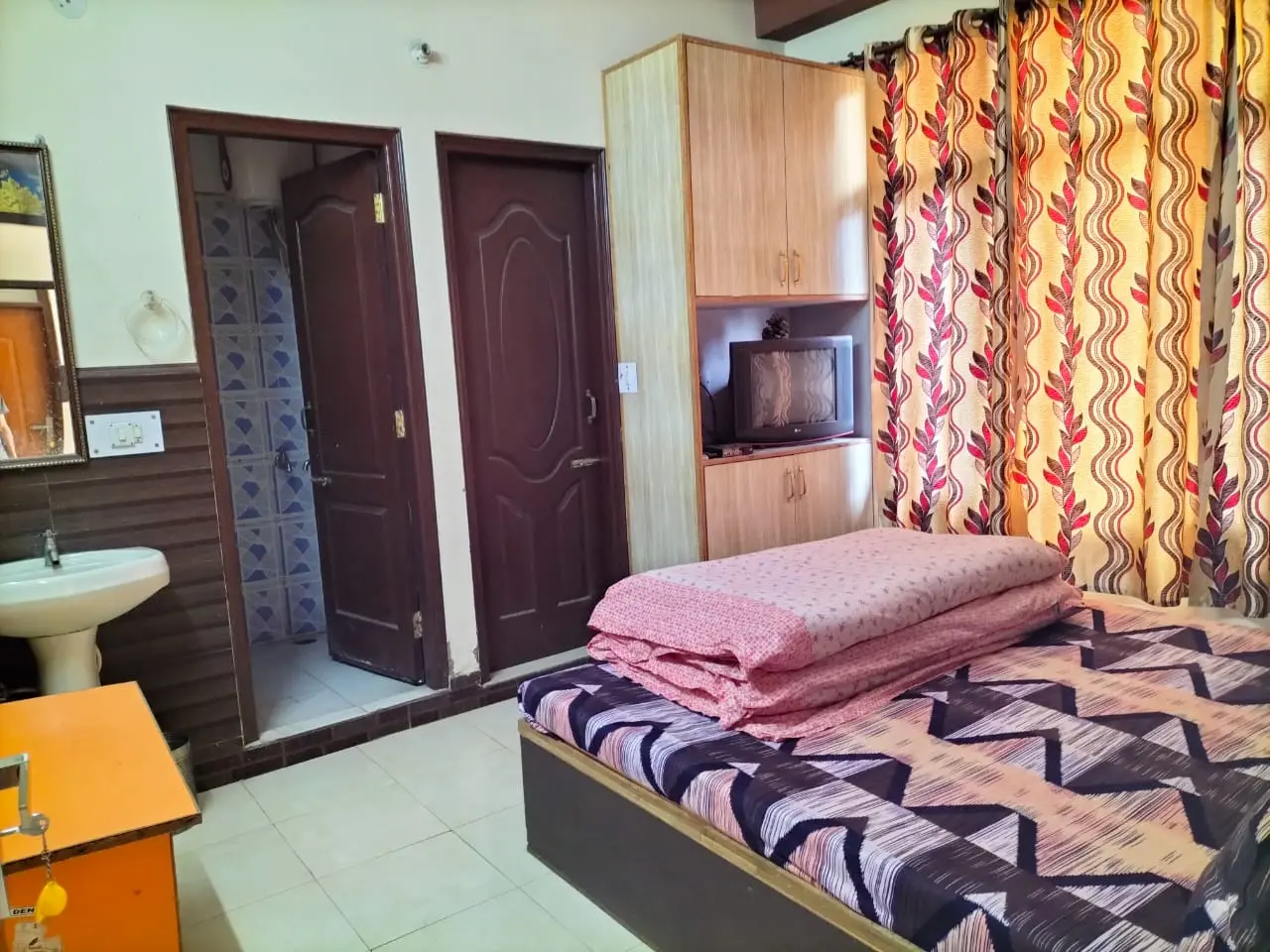 Deluxe room at Anupama Home Stay with double bed and adjoining wash area