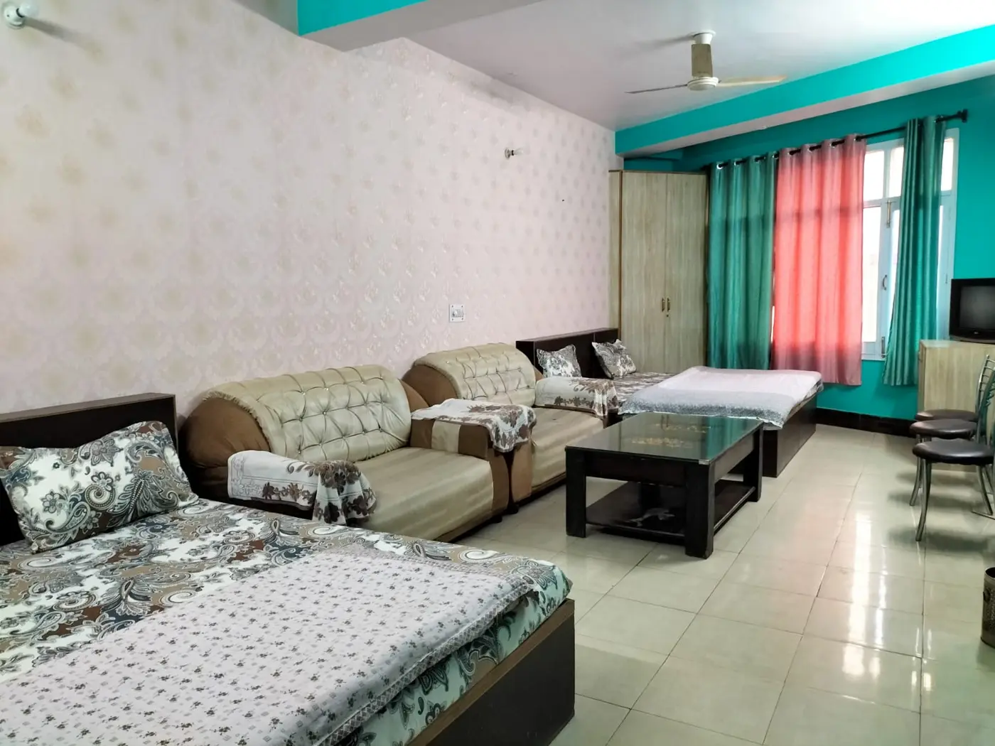 Family room interior at Anupama Home Stay with multiple beds and sofa seating